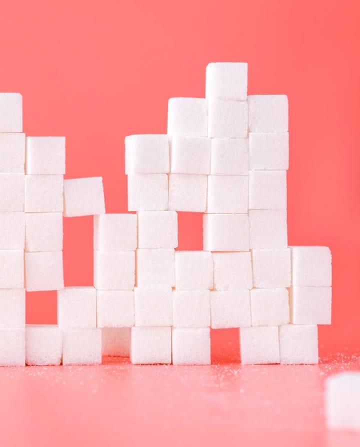 sugar cubes stacked in a pyramid on a pink background